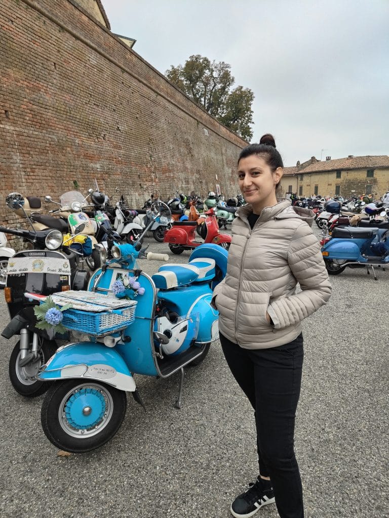 Aurélie, formatrice d'italien expatriée, devant des Vespa lors d'un événement public en Italie.