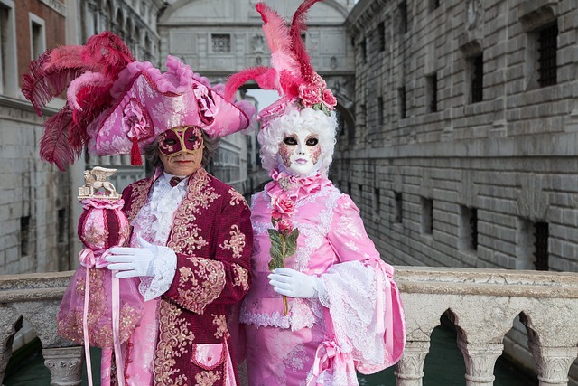 Deux personnages masqués en costumes rose et bordeaux prenant la pose sur un pont de Venise pendant le Carnaval
